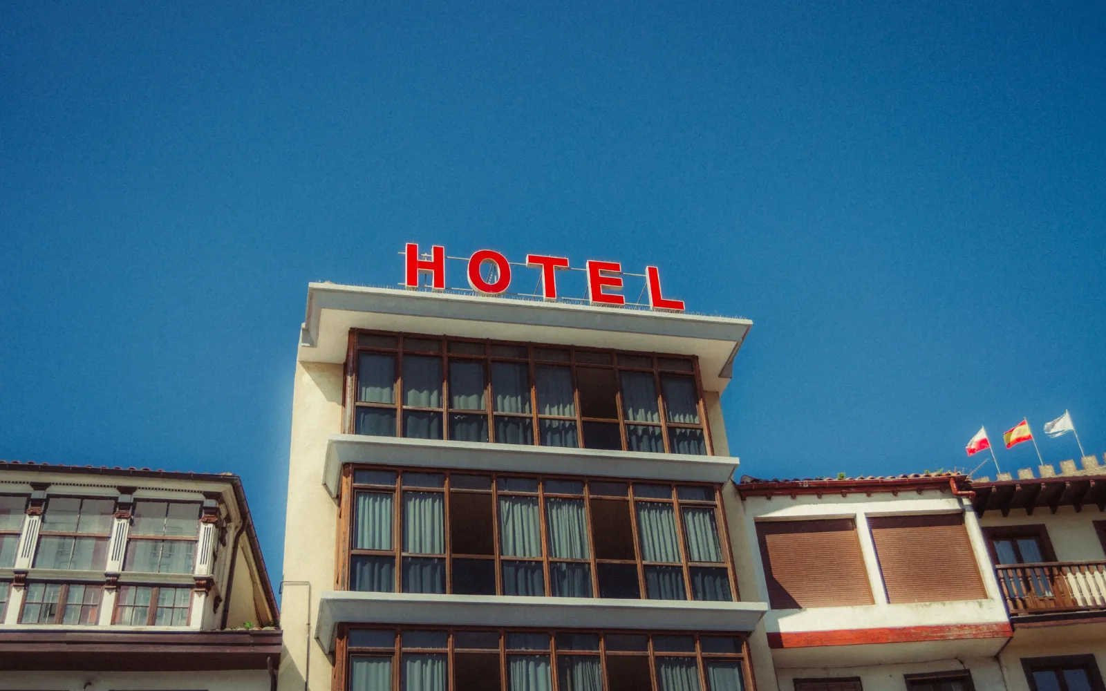 Colorful hotel facade in Asturias, Spain with bright signage against a clear sky.